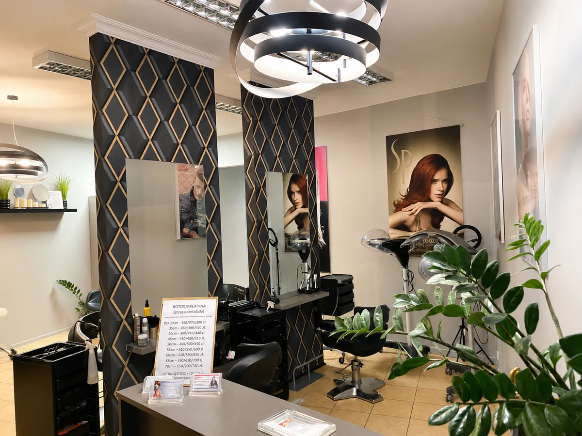 Część recepcyjna Salonu Glamour z cennikiem na ladzie, lustrami i zielenią